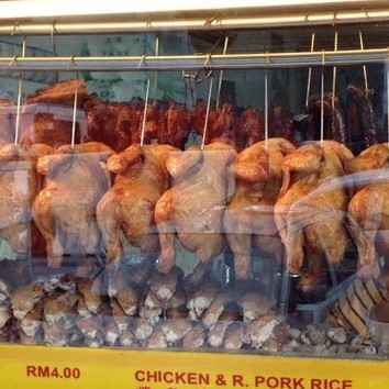 Roasted chickens displayed in front of a stall